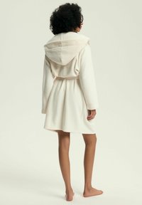 Szlafrok z kapturem wykonany z miękkiego, jasnoróżowego polaru. Posiada pasek w talii, długie rękawy oraz rozkloszowaną spódnicę sięgającą powyżej kolan.