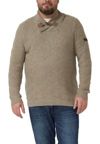 Beiger gestrickter Pullover mit strukturiertem Muster, Schalkragen und Holzknopfleisten. Kombiniert mit dunkelblauen Jeans.