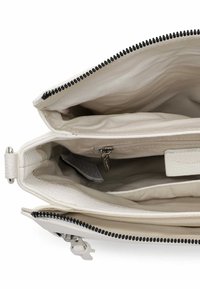 Hvidt lædertaskeinteriør med to hovedrum, beige foer og lynlåslomme. Har sort lynlåsdetaillering og beslag.