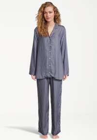 Marinblå randiga pyjamaser som har långärmad skjorta med knappar och löst sittande byxor med en mjuk yta och klassisk design.
