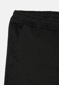 Pantalones negros con cinturilla elástica, con una textura suave y bolsillos laterales. El material parece duradero con un diseño clásico.