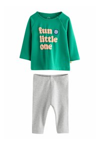 T-shirt pour bébé à manches longues vert avec le texte "petit espiègle" et un visage souriant, associé à des leggings rayés gris clair.
