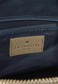 Navy stoffen interieur van een tas met een tan, gestructureerd leren label met de tekst "LAZAROTTI" in gouden letters; inclusief een ritsvak.