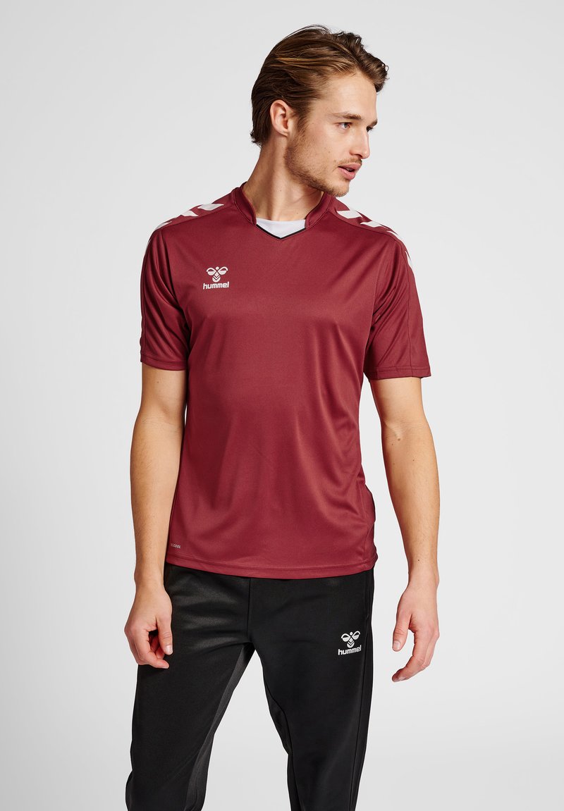 Bordeauxfarbenes Sportshirt mit kurzen Ärmeln, V-Ausschnitt und weißen Akzenten an den Schultern. Logo auf der linken Brust. Glatter Stoff.