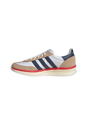 White and beige sneaker with navy blue stripes, red midsole accent, white laces, and a white sole with textured grip.