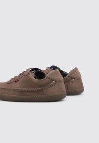 Chaussures en cuir marron avec une finition texturée, bout rond et design bas. Présente des accents cousus et une semelle en caoutchouc.
