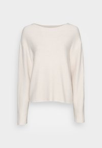 Pitkähihaisessa, vaaleanbeigeissä neulepaidassa on pyöreä kaula-aukko, väljä istuvuus ja hieman roikkuvat olkasaumat yksinkertaista taustaa vasten.