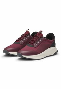 Maroon athletic shoes with a mesh upper, rubber sole, and gray accents. Features laces, subtle branding, and textured panels for grip.