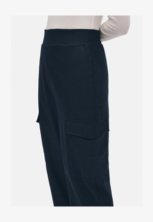 Pantalones cargo azul marino con una cintura ancha, bolsillos laterales y una textura suave, mostrados de lado.