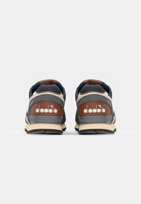 Adidași pentru bărbați din piele marină, gri și maro; cu un călcâi căptușit, accente texturate și o talpă din cauciuc cu detalii ale logo-ului.