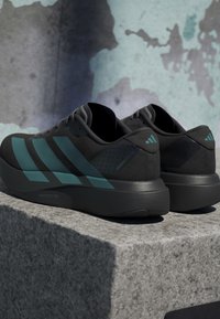 Czarne buty sportowe z akcentami w kolorze teal, teksturowana cholewka i lekką podeszwą. Posiadają trzy tealtowe paski oraz perforowane detale na pięcie.