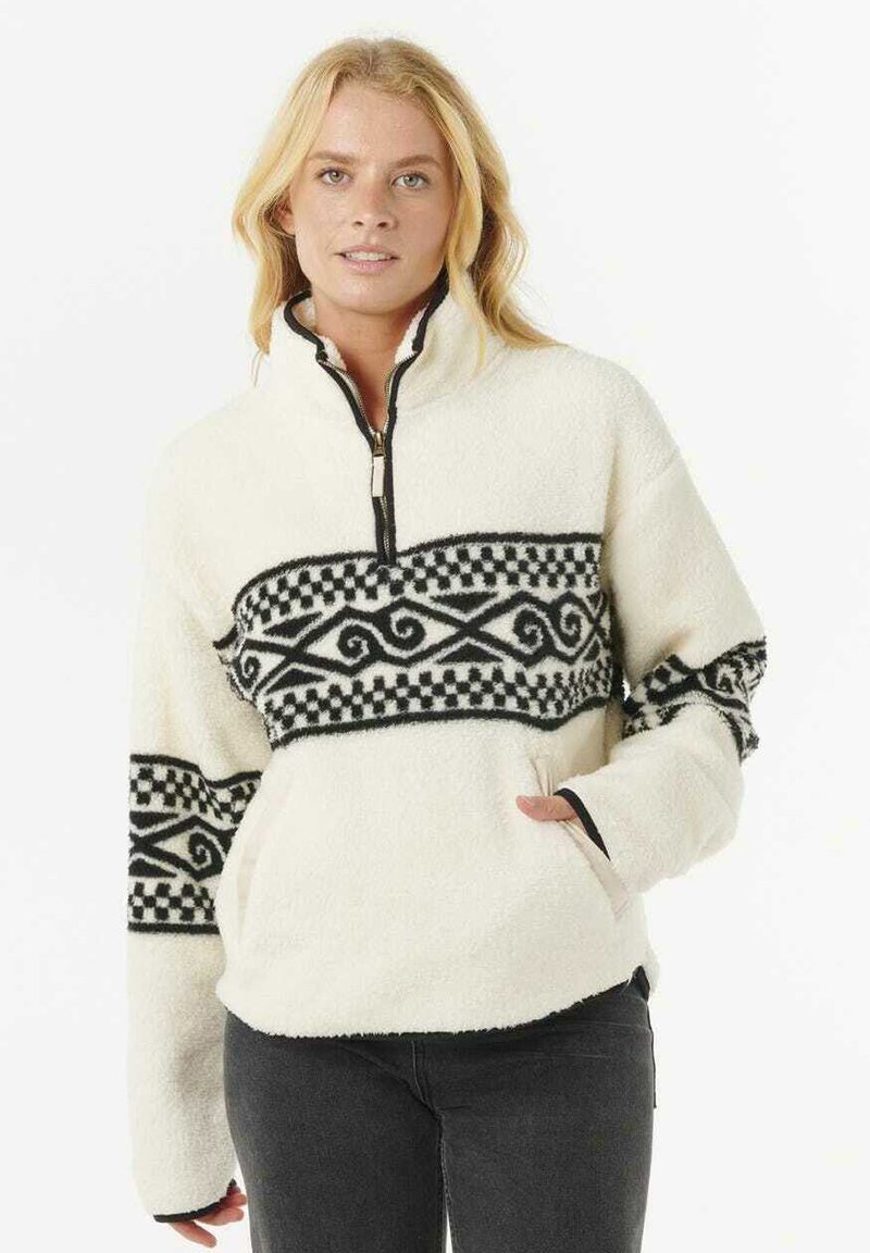 Pull en polaire avec col zippé, couleur crème, rayure noire à motifs de tourbillons et de carrés, et poches latérales. Texture douce.