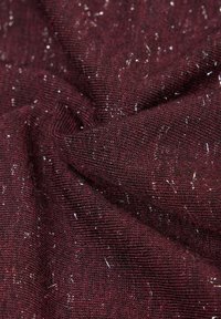Nahaufnahme von dunkelrotem Strickstoff mit verstreutem silbernem Glitzerfaden, der durchgewebt ist.