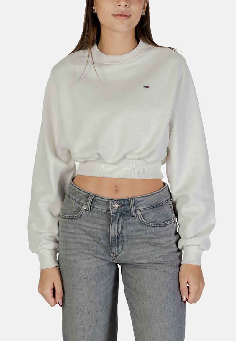 Felpa bianca corta con scollo rotondo e orlo a costine. Abbinata a jeans di denim grigi a vita alta con un classico design a cinque tasche.