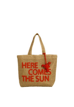 Bolsa tote tejida beige con asas y texto rojo "HERE COMES THE SUN" más un pequeño llavero rojo con forma de langosta.