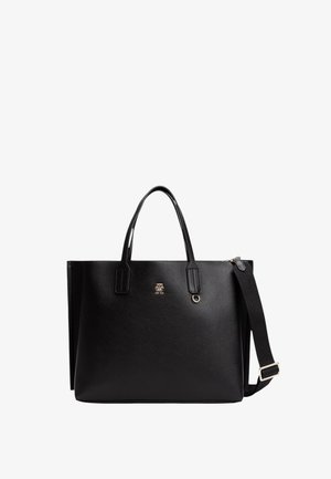 Czarna skórzana torba tote z dwoma uchwytami i odpinanym paskiem na ramię. Złote logo na przodzie. Gładka tekstura i wyraźny kształt.