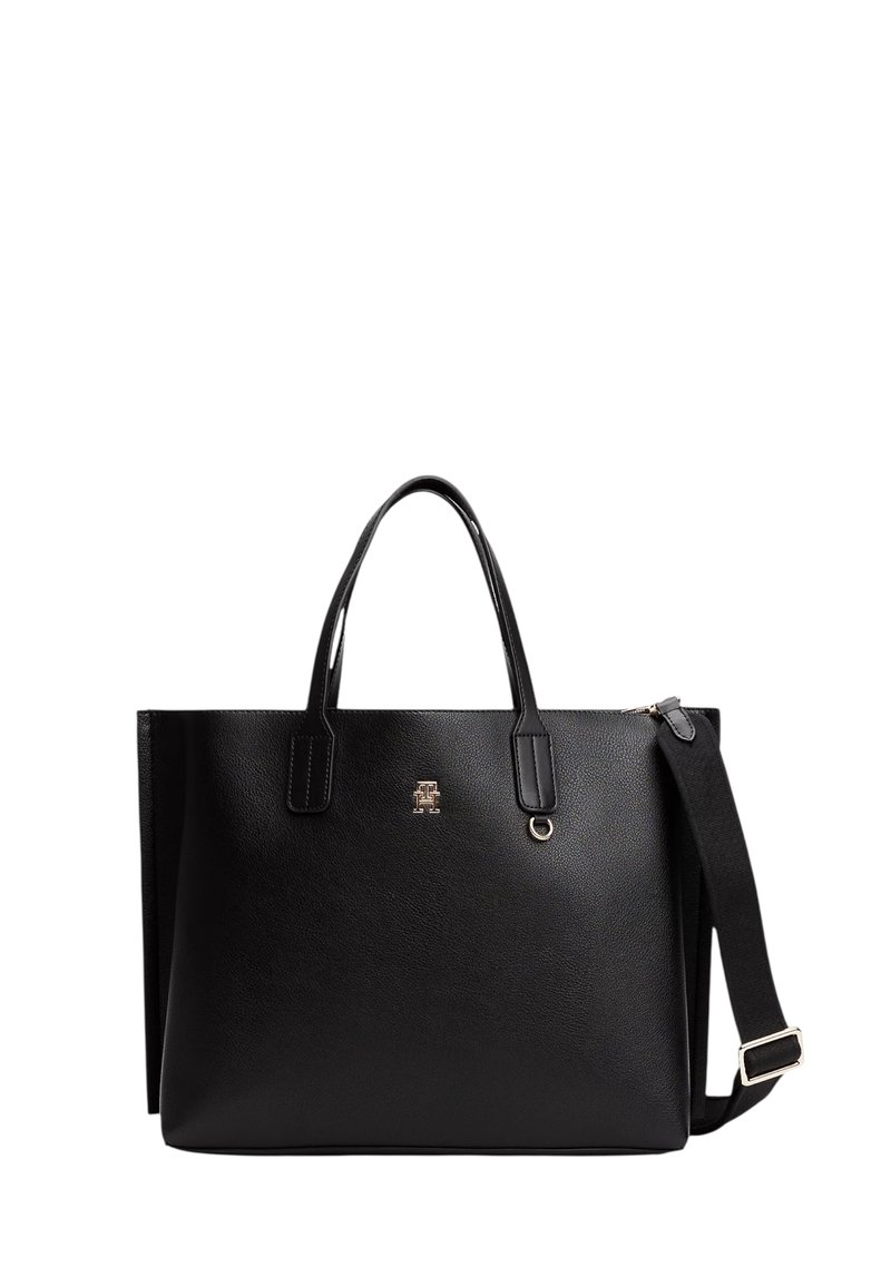 Zwarte leren tote bag met twee handvatten en een afneembare schouderband. Gouden logo in detail aan de voorkant. Gladde textuur en gestructureerde vorm.