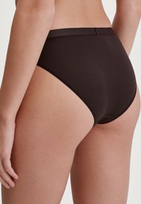Mutande nere a vita alta con una texture liscia, elastico in vita e senza cuciture visibili; progettate per comfort e una vestibilità sicura.