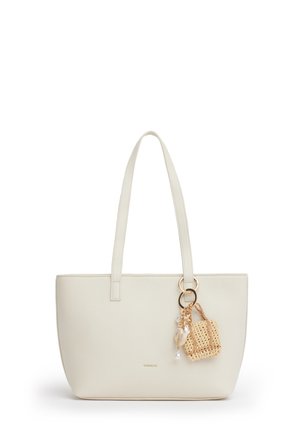 Borsa a tracolla color crema con manici lunghi e un piccolo portachiavi intrecciato con perline attaccato a un anello dorato.