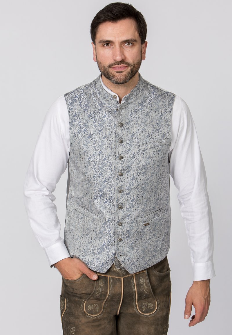 Blaues Paisley-Muster-Weste mit Stehkragen, Knöpfen auf der Vorderseite und zwei Taschen, getragen über einem weißen Hemd. Braune Hosen runden den Look ab.