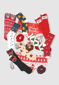 Calze e biancheria intima a tema natalizio in rosso e verde, con motivi come renne, Babbo Natale e biscotti di pan di zenzero, accompagnati da accessori come scrunchies.