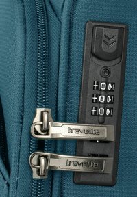 Turquoise koffer ritsdetail met twee zilveren sloten, een zwarte combinatieslotpaneel en een gestructureerd stoffenoppervlak.