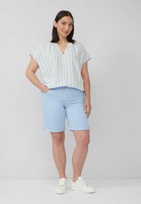 Haut à rayures bleu clair à manches courtes, avec un col en V et une coupe décontractée, associé à un short bleu clair à manches retroussées et des baskets blanches.