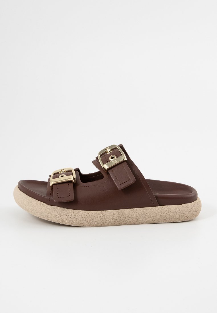 Braune Slide-Sandalen mit zwei Schnallenriemen, einem glatten Leder-Obermaterial und einer strukturierten, tanfarbenen Gummisohle. Goldene Beschläge setzen Akzente.