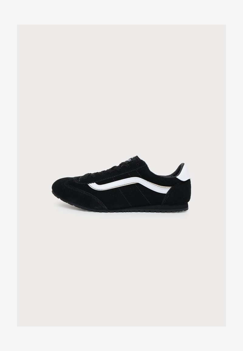 Baskets basses noires avec une bande blanche sur le côté et un onglet au talon, fermeture à lacets et semelle texturée, vues en profil gauche sur fond blanc.