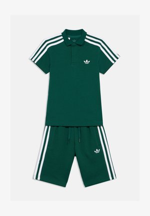 Zelené bavlněné polo triko s bílými pruhy na ramenou, s klasickým límcem a malým logem. V kombinaci s odpovídajícími šortkami s nastavitelným pasem.