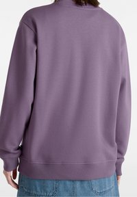 Sudadera morada con cuello y puños acanalados, que presenta un ajuste holgado y una textura suave. Confeccionada con una tela cómoda.