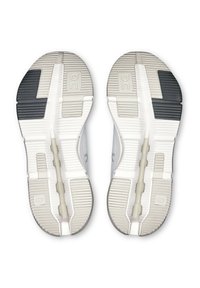 Sohlen von weißen und grauen Sportschuhen mit Stollenmustern, schwarzen Griffbereichen und einer zentralen "Speedboard"-Stützleiste sichtbar.
