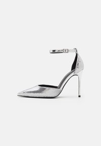 Zilveren hoge hakken met een spitse neus, gestructureerde metallic afwerking, enkelbandje en glanzende stilettohak. Zwarte binnenvoering.