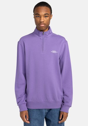 Purple half-zip sweatshirt with ribbed cuffs and hem, featuring small white branding on the chest, made from soft fabric with a smooth texture.