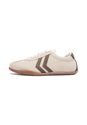 Baskets beige profil bas avec des bandes chevron marron, fermeture à lacets à l'avant et semelle marron clair, vues de côté sur fond blanc.