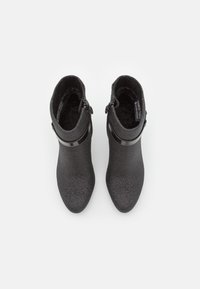 Bottines noires à la cheville avec une finition texturée, dotées d'une bande noire brillante et d'un détail zippé, d'une conception à bout pointu et d'une doublure en peluche.