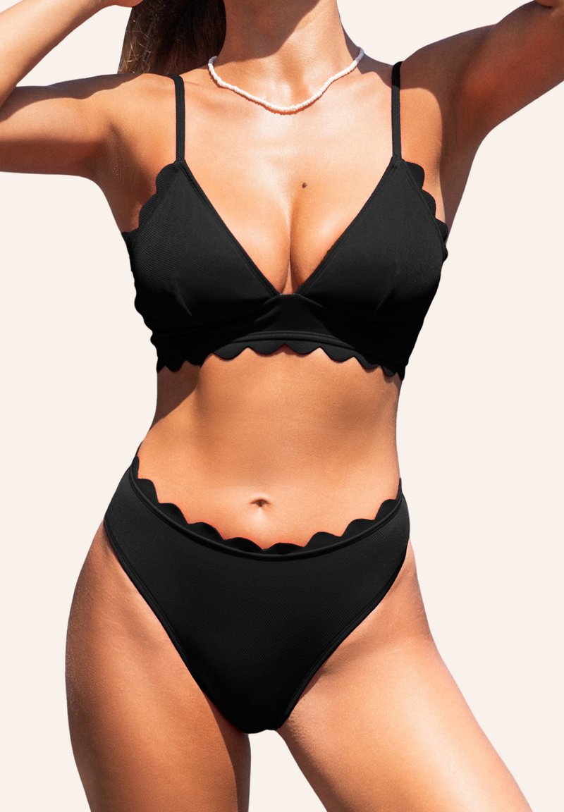 Completo bikini nero con margini ondulati, spalline regolabili e texture a coste. Il top ha una forma triangolare e presenta un design a V.