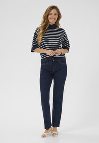 Navy and white striped short-sleeve top, round neckline, paired with dark blue straight-leg jeans and light-colored sandals.