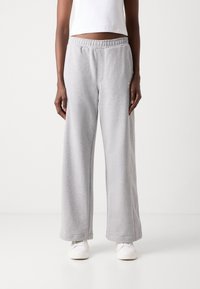 Pilkos plačios kojų sweatpants kelnės, pagamintos iš minkštos medvilnės mišinio, su elastinga juosmens juosta, šoninėmis kišenėmis ir laisvu siluetu. Tinka kasdieniam dėvėjimui.