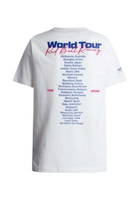 Camiseta blanca con el texto "World Tour Red Bull Racing 2026" y una lista de ubicaciones de carreras globales impresas en la parte posterior en texto azul y rojo.