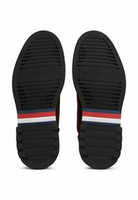 Czarna gumowa podeszwa z teksturowanymi rowkami i trójkolorowym paskiem w kolorach czerwonym, białym i niebieskim na śródpodeszwie z wytłoczonym napisem "TOMMY HILFIGER".