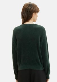 Diepgroene, textuurgevelde trui met lange mouwen en een ronde halslijn. Heeft een losse pasvorm en zachte, fluffy stof.