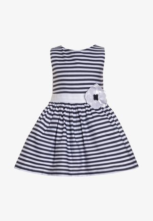 Robe sans manches à rayures horizontales noires et blanches avec une jupe froncée, une ceinture blanche et une fleur blanche décorative sur le côté droit.