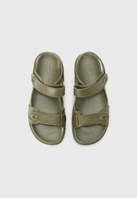 Sandal hijau zaitun dengan tali yang dapat disesuaikan, bahan plastik halus, bentuk bulat, dan rincian logo pada tali.