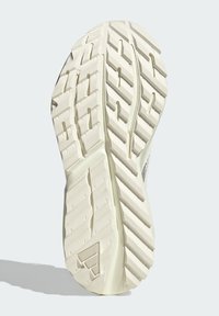 Guma podešva tenisky s dezénom, ktorý obsahuje diagonálne a horizontálne drážky. Farba je krémová s textúrovanými detailmi a logom.