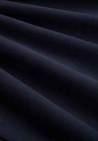 Tessuto blu navy con una trama liscia, caratterizzato da onde e pieghe sottili, che mettono in risalto la flessibilità e la morbidezza del materiale.