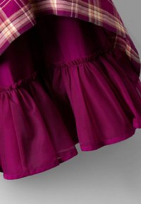 Rochie de culoare prună, cu un strat plisat din țesătură în carouri la tiv, fabricată dintr-un material ușor cu o textură plisată.