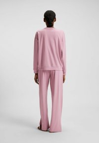 Completo da lounge rosa con maniche lunghe e pantaloni a vestibilità morbida con slit laterali, realizzato in tessuto liscio e leggero.