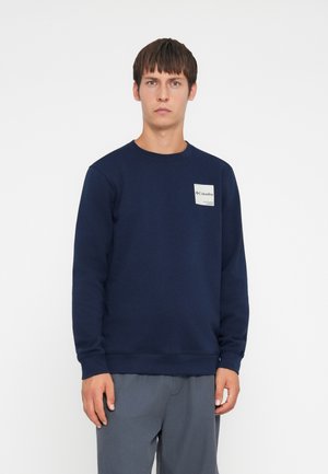 Navy blue sweatshirt made of cotton blend, featuring a crew neckline and ribbed cuffs. Includes a small logo patch on the chest.