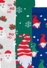 Three pairs of festive socks: gray with Santa and text, green with snowflakes and gifts, blue with smiling gnomes and snowy accents.